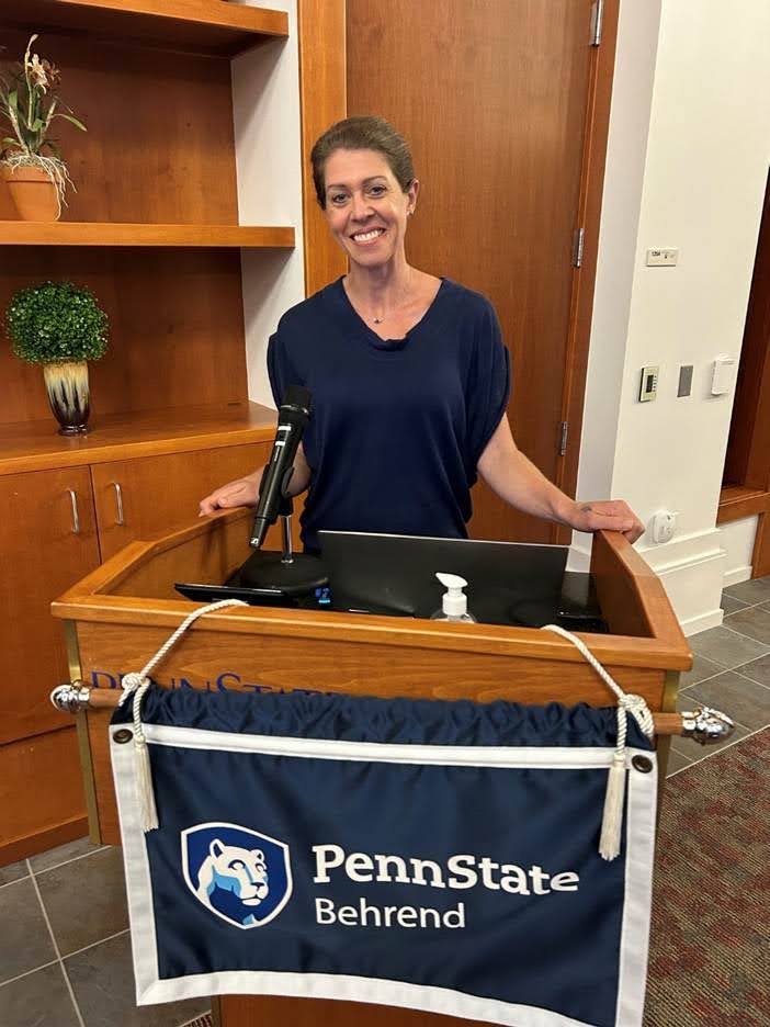 Elizabeth Hazen smiling while standing behind a Pennstate Behrend podium